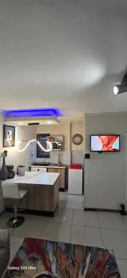 a living room with a kitchen with a table at Okoli's Place in Sandown