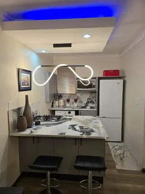 a kitchen with a counter with two stools in it at Okoli's Place in Sandown