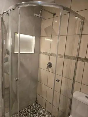 a shower with a glass door in a bathroom at Okoli's Place in Sandown