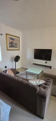 a living room with a brown couch and a flat screen tv at Okoli's Place in Sandown