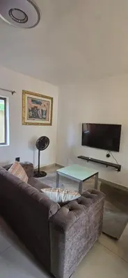 a living room with a brown couch and a flat screen tv at Okoli's Place in Sandown