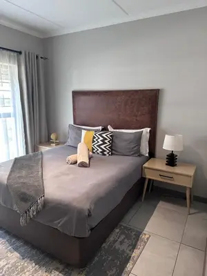 a bedroom with a large bed with a wooden headboard at Large 3 Bedroom Apartment in Midrand, Waterfall City - More space than a hotel room - Ideal for families, groups and work trips - 18A Elizabeth Place in Midrand