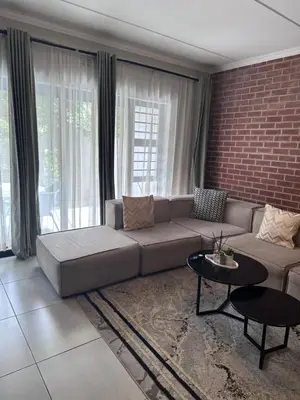 a living room with a couch and a brick wall at Large 3 Bedroom Apartment in Midrand, Waterfall City - More space than a hotel room - Ideal for families, groups and work trips - 18A Elizabeth Place in Midrand