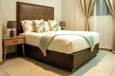 a bedroom with a large bed with a wooden headboard at Spacious 2 Bedroom Apartment in Midrand, Waterfall City - Business and Family friendly - 14A Elizabeth Place in Midrand