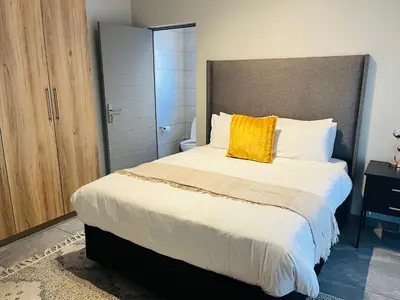a bedroom with a large bed with a yellow pillow at Secure 1 Bedroom Apartment in Midrand, Waterfall City - Lock Up and Go - Free WIFI and Parking - 6A Elizabeth Place in Midrand