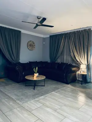 a living room with a black couch and a table at 23 On Jupiter in Polokwane