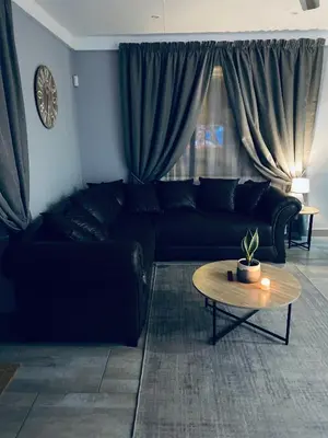 a living room with a black couch and a table at 23 On Jupiter in Polokwane