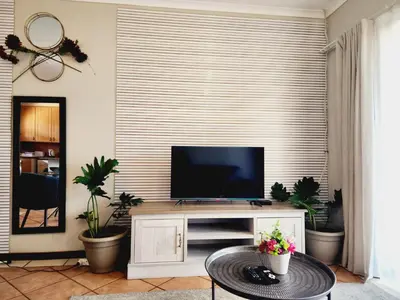 a living room with a flat screen tv on a entertainment center at Sable woods in Pretoria