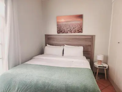 a bedroom with a bed with a green and white blanket at Sable woods in Pretoria