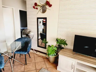 a living room with a tv and a mirror at Sable woods in Pretoria