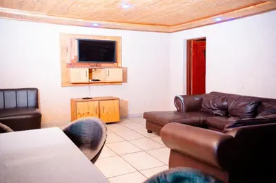 a living room with a couch and a television at Falcon Lodge Bela Bela in Merinovlakte