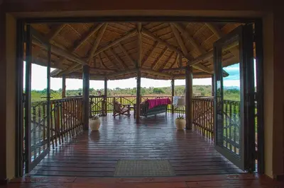 a large wooden porch with a table and chairs on it at Majuli River Lodge - overlooking Kruger Park in Marloth Park
