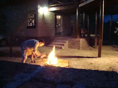 a man standing around a fire in a yard at Majuli River Lodge - overlooking Kruger Park in Marloth Park