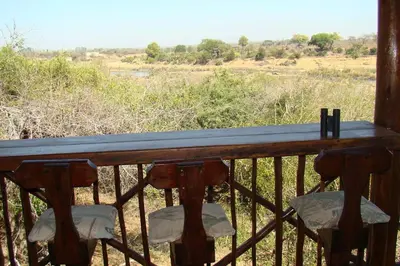 a wooden table with two chairs on a balcony at Majuli River Lodge - overlooking Kruger Park in Marloth Park