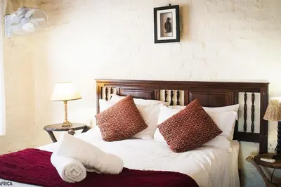 a bed with brown and white pillows on it at Majuli River Lodge - overlooking Kruger Park in Marloth Park