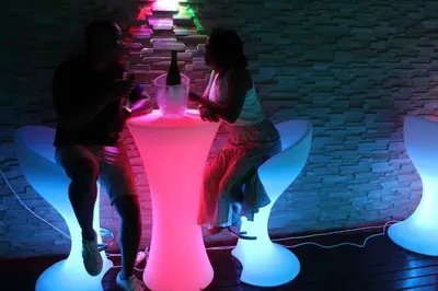 a man and woman sitting next to a pink lighted table at Falcon Lodge ET in Bela-Bela