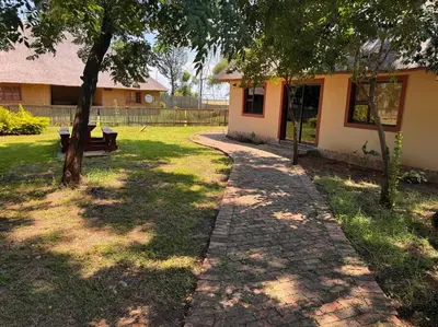 a brick path leading to a house with a bench at Falcon Lodge ET in Bela-Bela