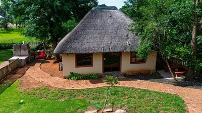 a small house with a thatched roof in a yard at Falcon Lodge ET in Bela-Bela