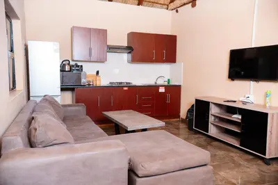 a living room with a couch and a kitchen at Falcon Lodge ET in Bela-Bela