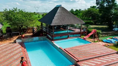 a swimming pool with a gazebo and a playground at Falcon Lodge ET in Bela-Bela