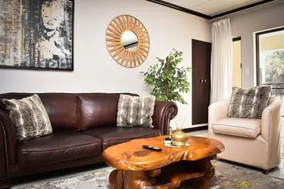 a living room with a brown leather couch and a table at Walford Estate, Spacious Private, Modern luxury living in Midrand