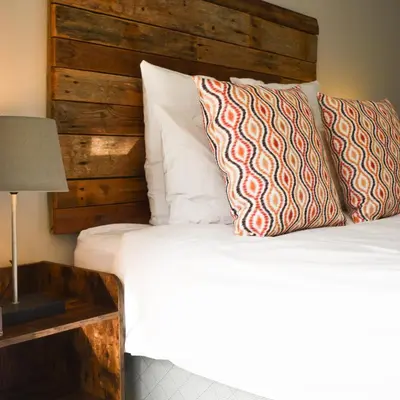 a bed with a wooden headboard and two pillows at Walford Estate, Spacious Private, Modern luxury living in Midrand