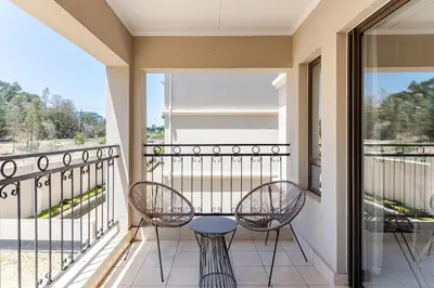 a balcony with two chairs and a table at Walford Estate, Spacious Private, Modern luxury living in Midrand