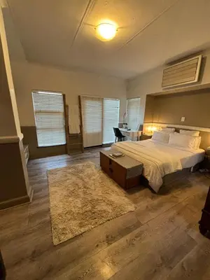 a bedroom with a bed and a desk with a table at Spacious Room in Pretoria East in Pretoria
