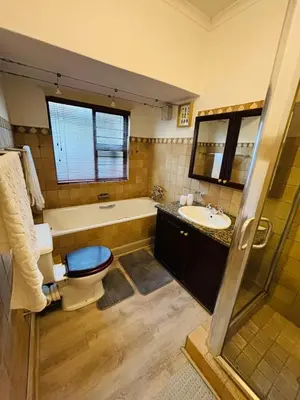 a bathroom with a tub and a toilet and a sink at Spacious Room in Pretoria East in Pretoria