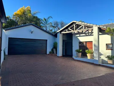 a house with a garage and a brick driveway at Spacious Room in Pretoria East in Pretoria