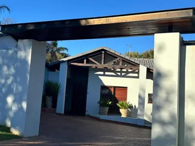 a white house with a wooden pergola at Spacious Room in Pretoria East in Pretoria