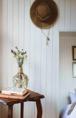 a hat and a table with a vase and books at Die Boothuis at Lake Chrissie in Lake Chrissie
