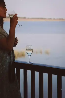 a woman standing on a balcony with a wine glass at Die Boothuis at Lake Chrissie in Lake Chrissie