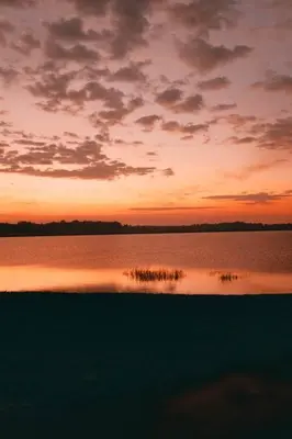 a sunset over a large body of water with grass at Die Boothuis at Lake Chrissie in Lake Chrissie