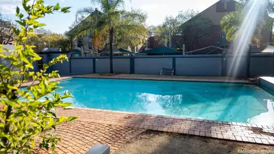 a swimming pool with a fountain in a backyard at Premium Getaway at Menlyn Maine in Pretoria