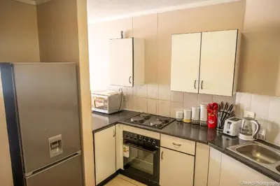 a kitchen with white cabinets and a stainless steel refrigerator at Premium Getaway at Menlyn Maine in Pretoria