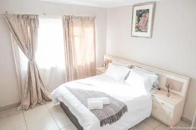 a white bedroom with a bed and a window at Premium Getaway at Menlyn Maine in Pretoria