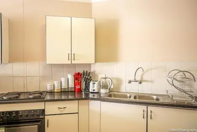 a kitchen with white cabinets and a sink at Premium Getaway at Menlyn Maine in Pretoria