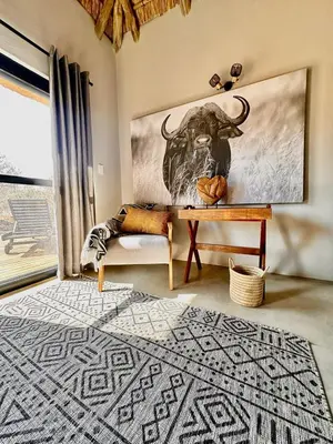 a living room with a table and a bull on the wall at Pumba Lodge Hoedspruit in Hoedspruit