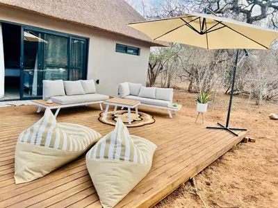 a wooden deck with a table and an umbrella at Pumba Lodge Hoedspruit in Hoedspruit