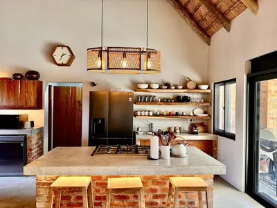 a kitchen with a large counter with stools in it at Pumba Lodge Hoedspruit in Hoedspruit