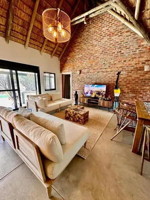 a living room with a couch and a brick wall at Pumba Lodge Hoedspruit in Hoedspruit