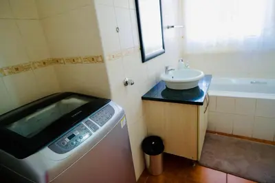 a small bathroom with a washing machine and a sink at Palm Haven 5 min drive to Carlswald Centre in Midrand