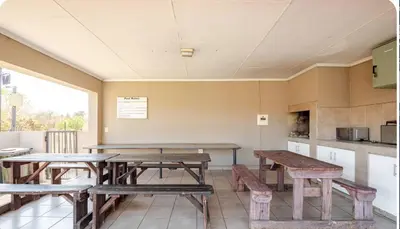 a room with wooden tables and benches and a kitchen at Palm Haven 5 min drive to Carlswald Centre in Midrand