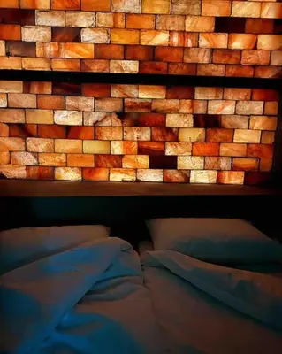 a brick wall above a bed in a bedroom at The Eco Hut in Hoedspruit