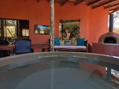 an outdoor hot tub in a house with a fireplace at The Eco Hut in Hoedspruit