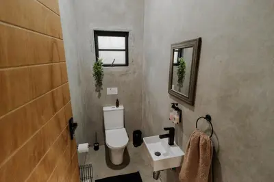 a bathroom with a white toilet and a sink at Afri Villa Stays - Luxury Bush Villa Bird in Marloth Park