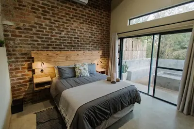 a brick walled bedroom with a bed and a window at Afri Villa Stays - Luxury Bush Villa Bird in Marloth Park