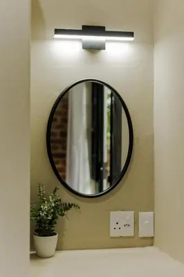 a mirror on a wall above a bathroom sink at Afri Villa Stays - Luxury Bush Villa Bird in Marloth Park