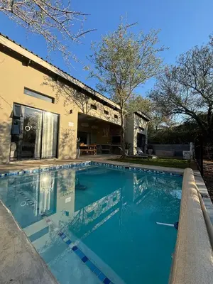 a swimming pool in front of a house at Afri Villa Stays - Luxury Bush Villa Bird in Marloth Park